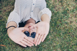 Woman lying in grass with hands up