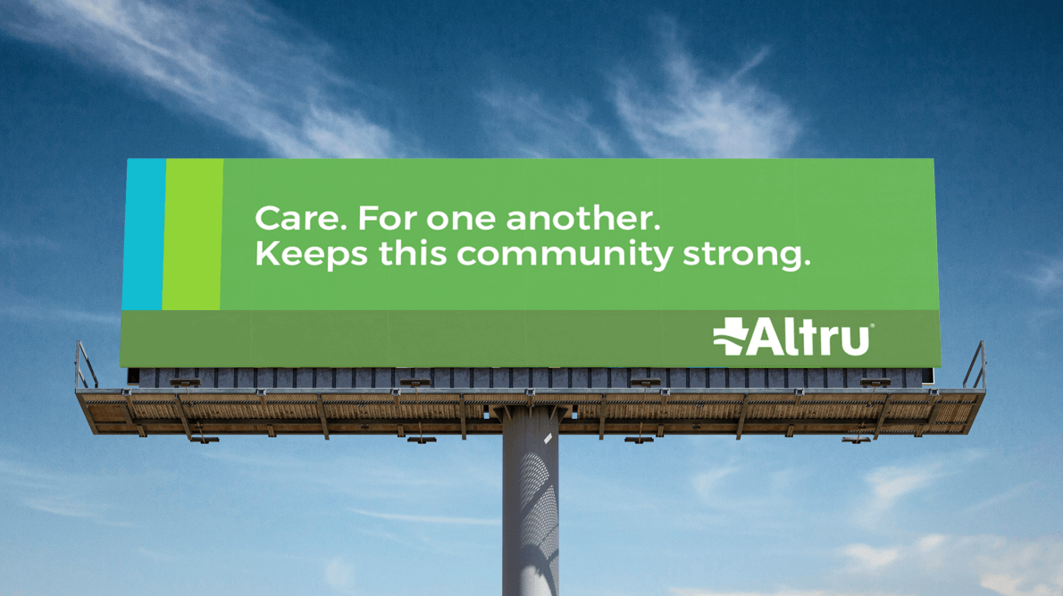 Billboard with multiple green and blue rectangular sections and text that reads, "Care. For one antoher. Keeps this community strong." There is also an Altru logo in the lower right corner.