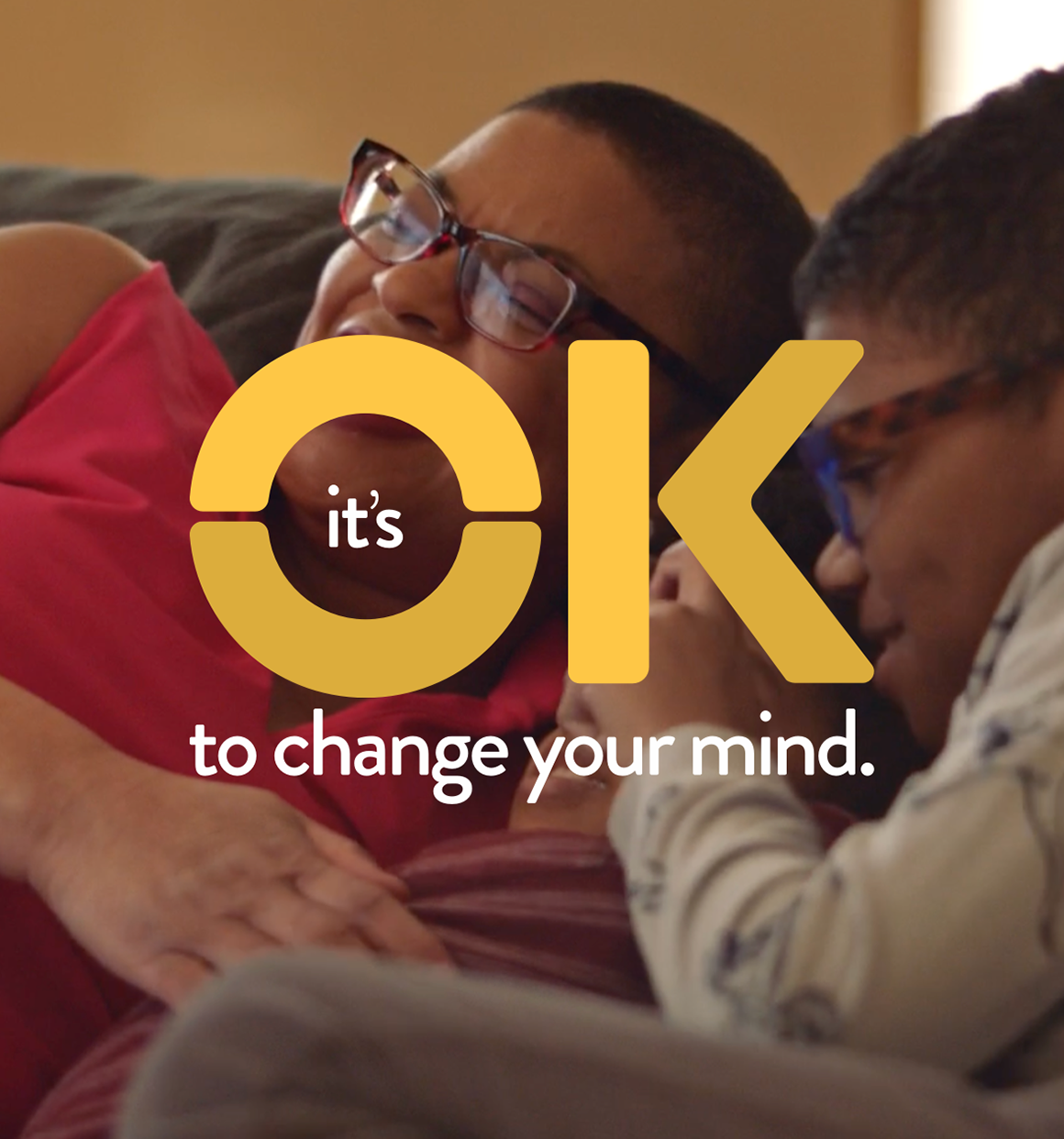 Woman with glasses and a pink shirt laughing with her two young kids on a couch with text over the image that says, "it's OK to change your mind."