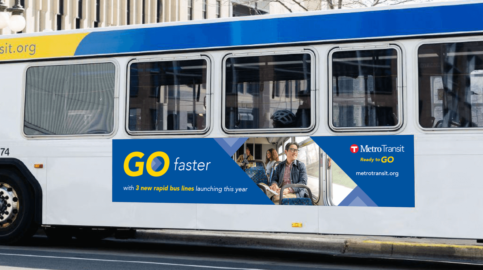 An ad on the side of a bus that reads, "GO faster with 2 new rapid bus lines launching this year," on a blue background with a photo of a man reading a book while riding the bus.