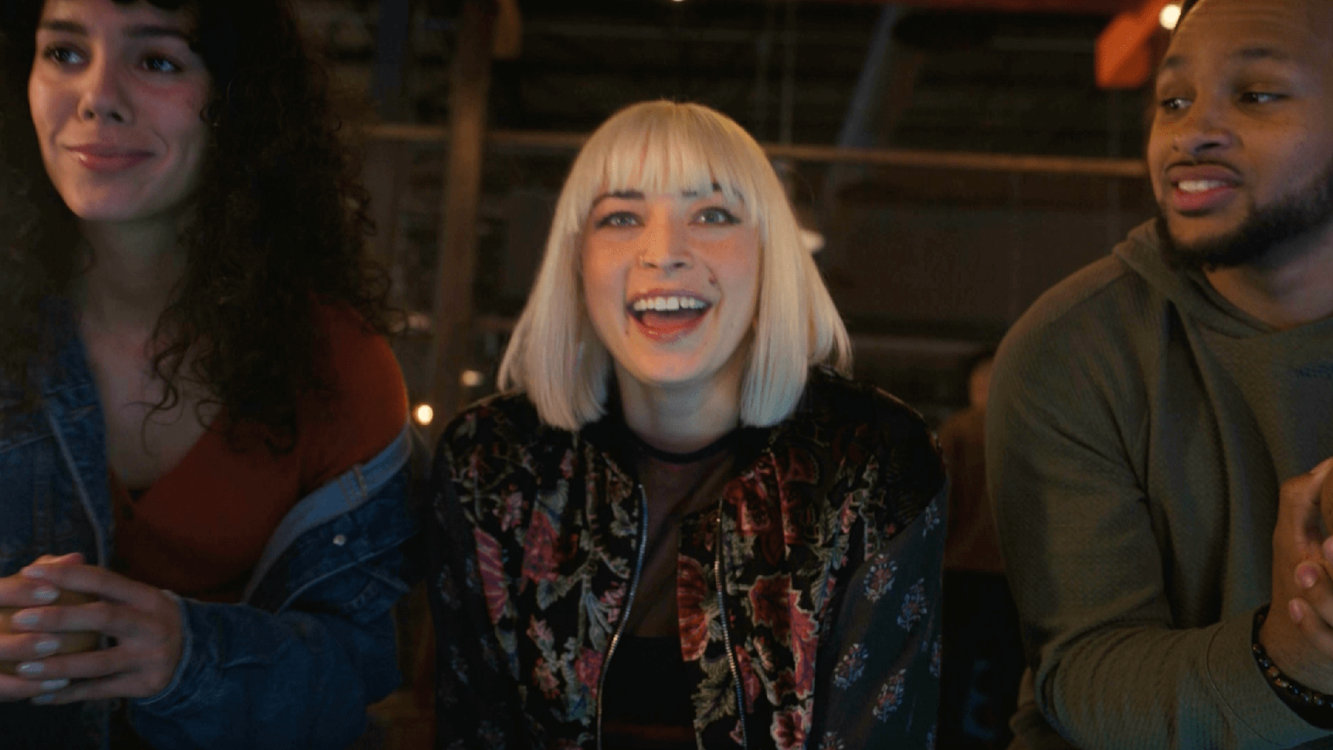 Close up of three friends leaning in. The one in the middle is poised to say, "GO!". She has short blonde hair. The other 2 friends are holding balls, preparing to throw them.