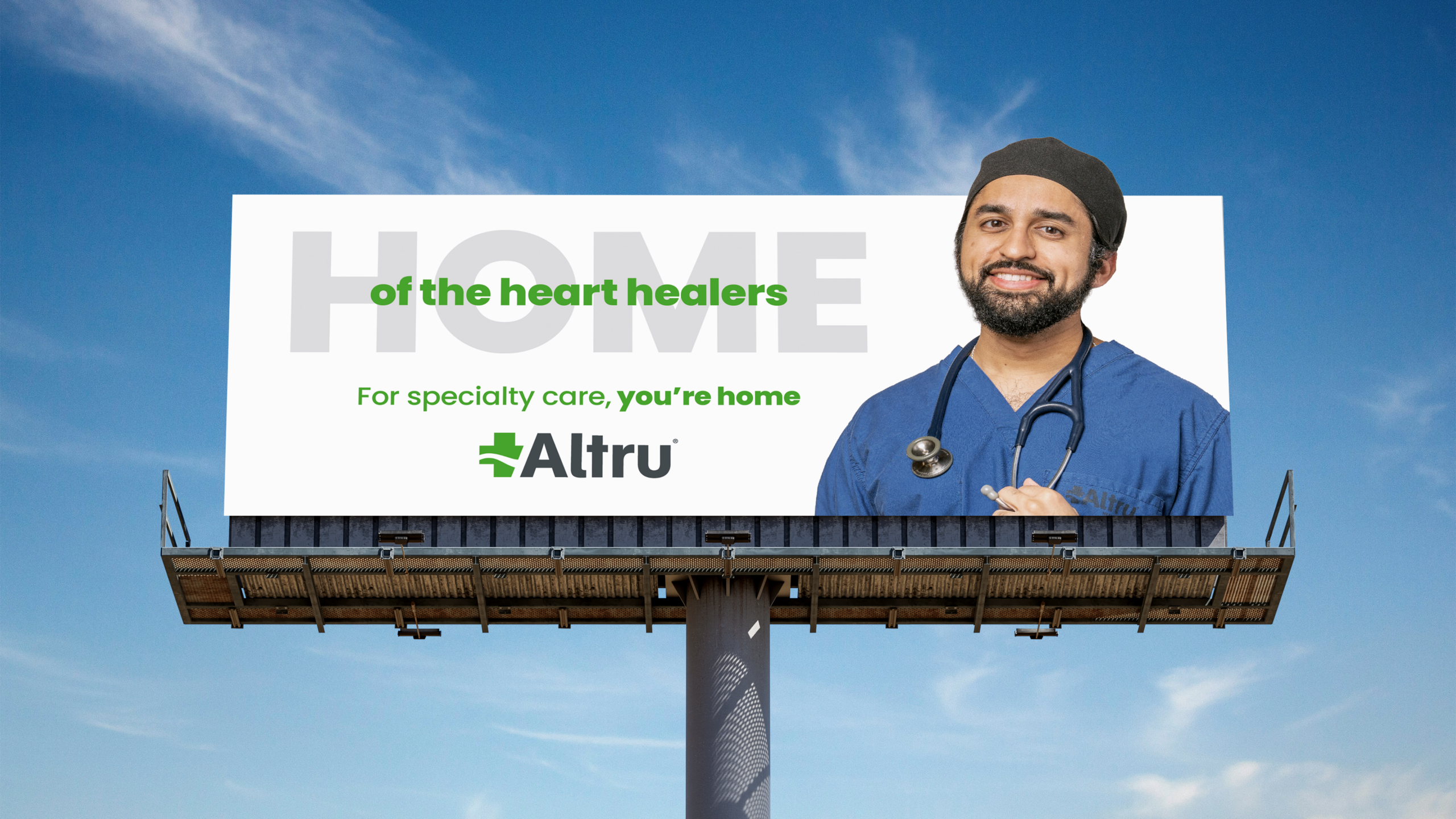 Billboard featuring a smiling healthcare professional in blue scrubs beside the message, “HOME of the heart healers. For specialty care, you're home,” with the Altru logo.